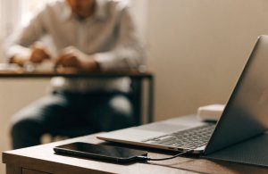 Celular conectado por cabo a um notebook sobre a mesa