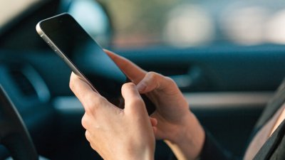 Tài xế đang kiểm tra điện thoại di động bên trong xe đang đỗ.