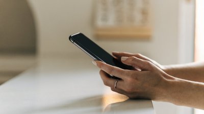 Mulher segurando o celular sobre a bancada do banheiro